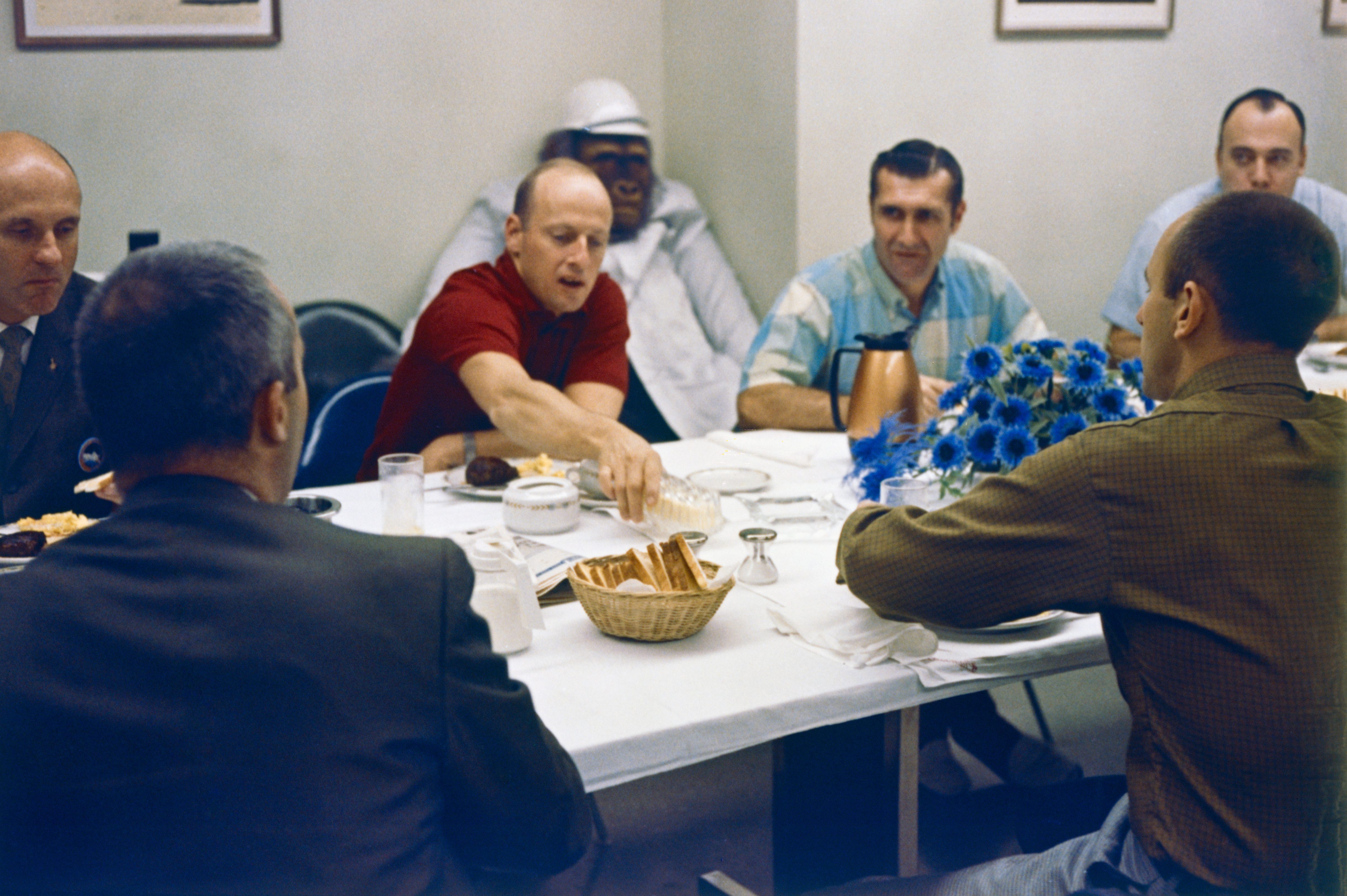 The Apollo 12 crew of Charles “Pete” Conrad, center, Richard F. Gordon, and Alan L. Bean, facing them, at the traditional prelaunch breakfast, with their mascot “Irving” behind Conrad