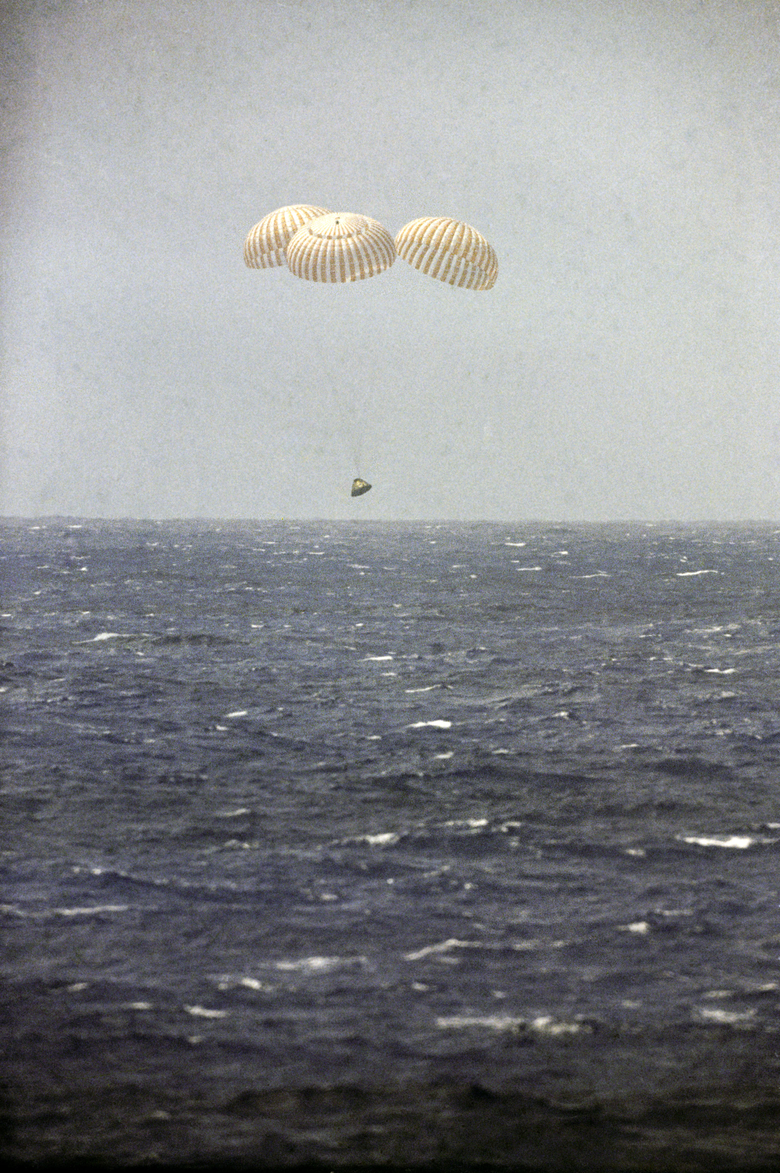 The Apollo 12 Command Module Yankee Clipper descends on its three main parachutes seconds before splashdown