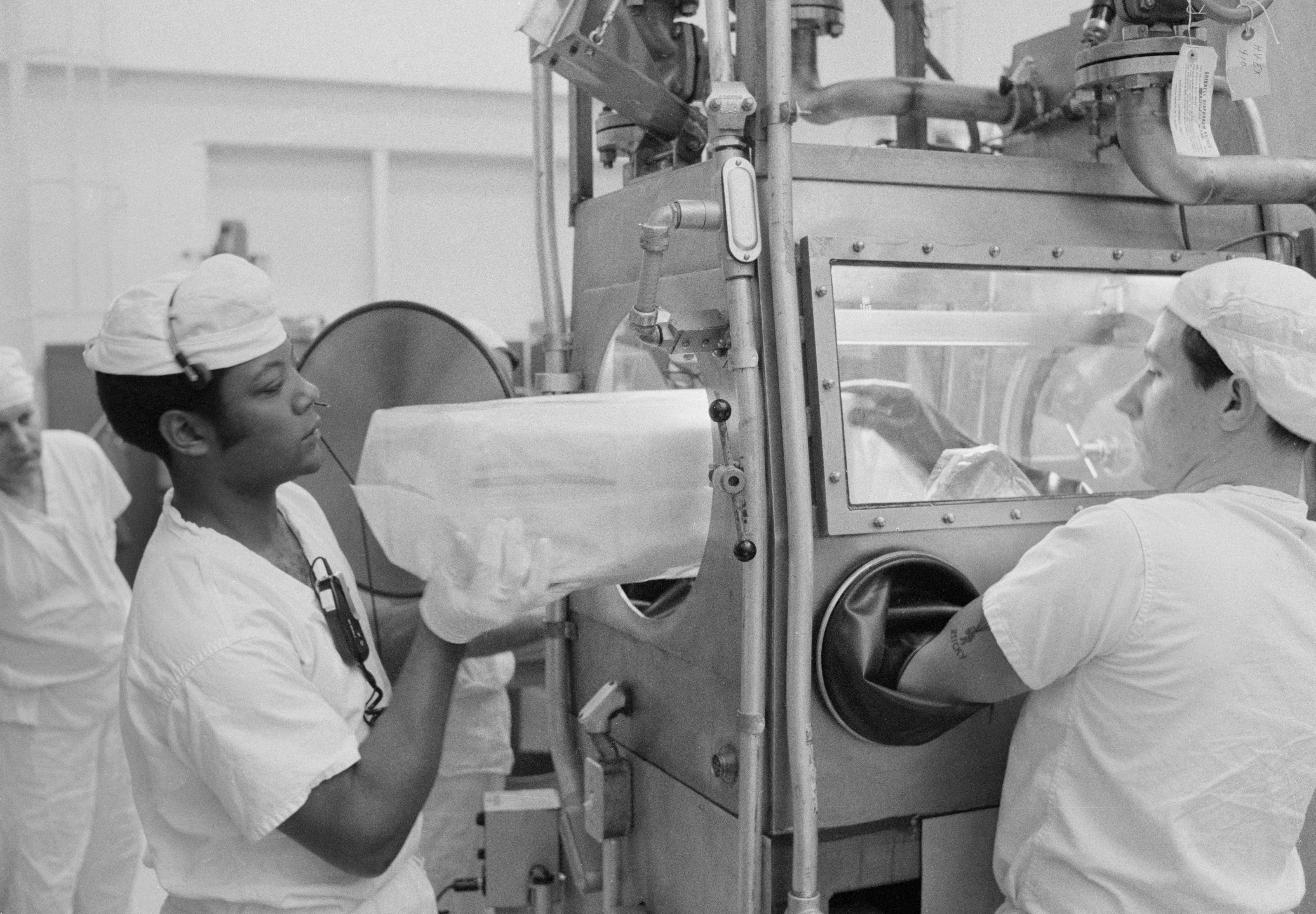 Technicians place the first Apollo 12 Sample Return Container (SRC) inside a glovebox at the Lunar Receiving Laboratory