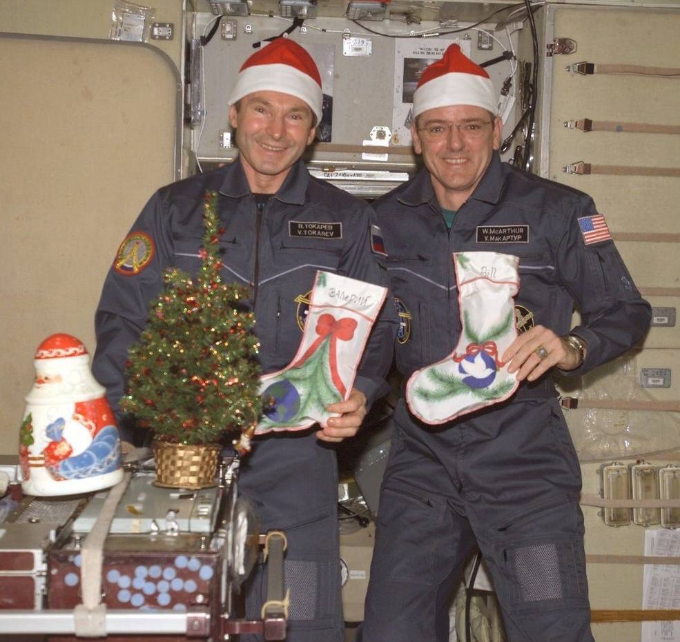 Two men in Santa hats pose with Christmas stockings