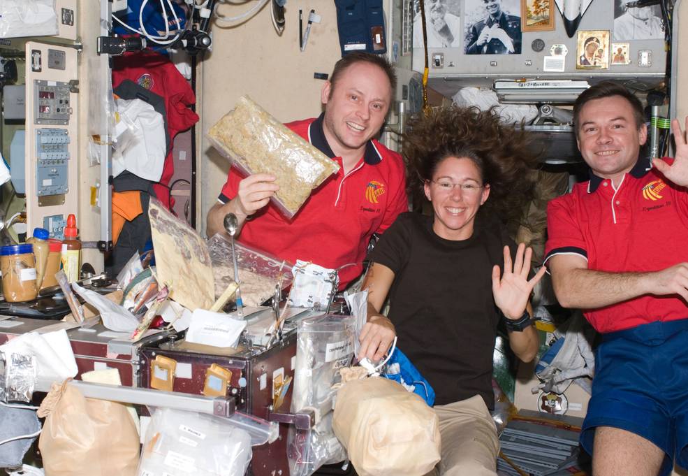 two men and one woman smile and wave as they celebrate Christmas