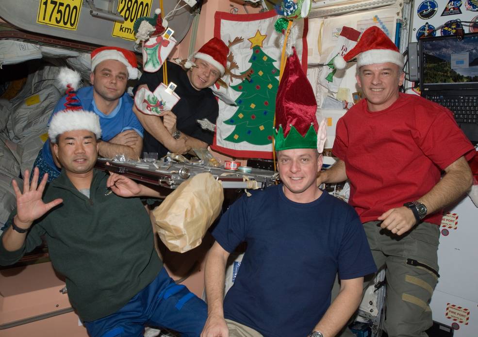 Several people with Santa hats pose for a Christmas picture on the International space Station