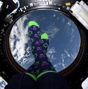 a pair of feet donned with blue and yellow hanukkah socks are shown in front of the cupola