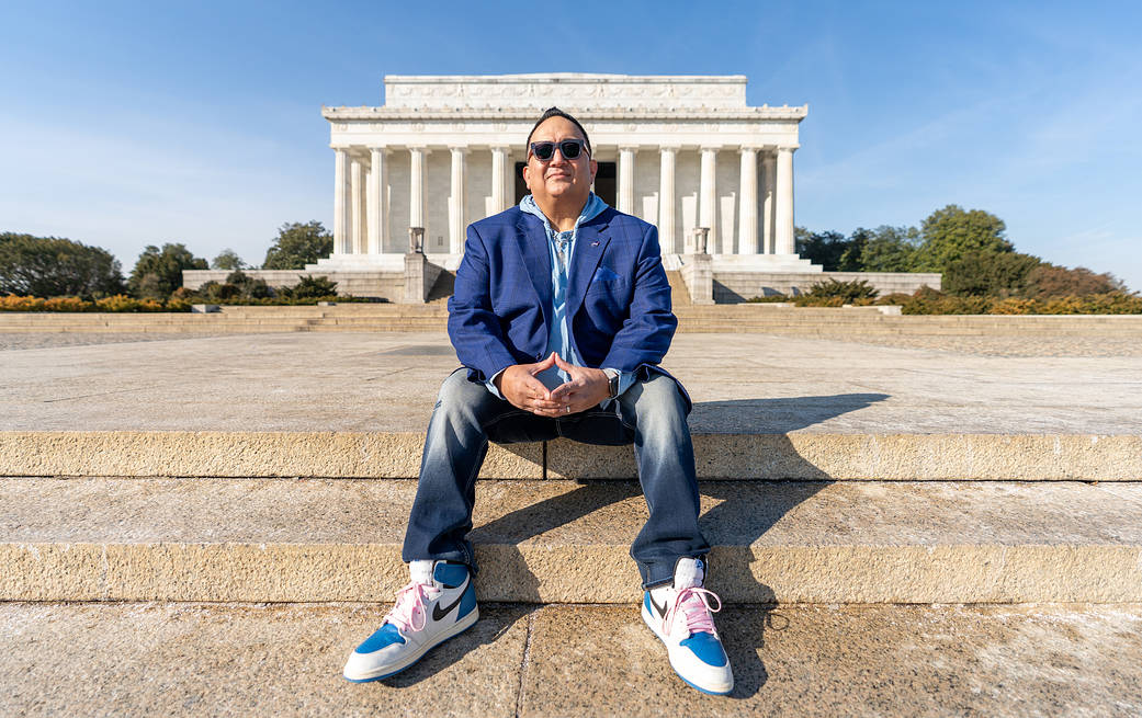 Edward Gonzales sitting with his hands folded on the steps in front of the Lincoln Memorial in Washington, DC. 