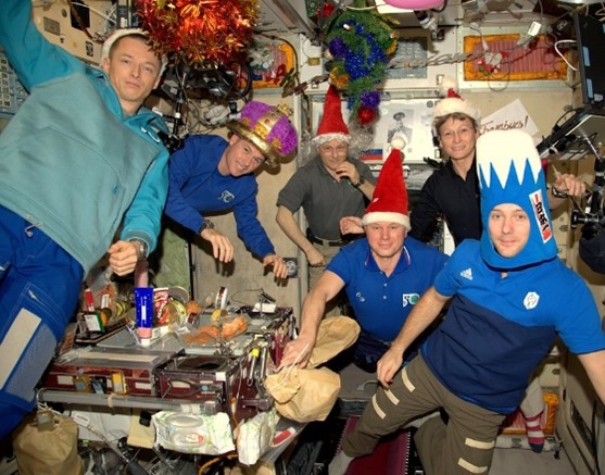 Several people wearing festive hats pose for a New Year's Eve picture