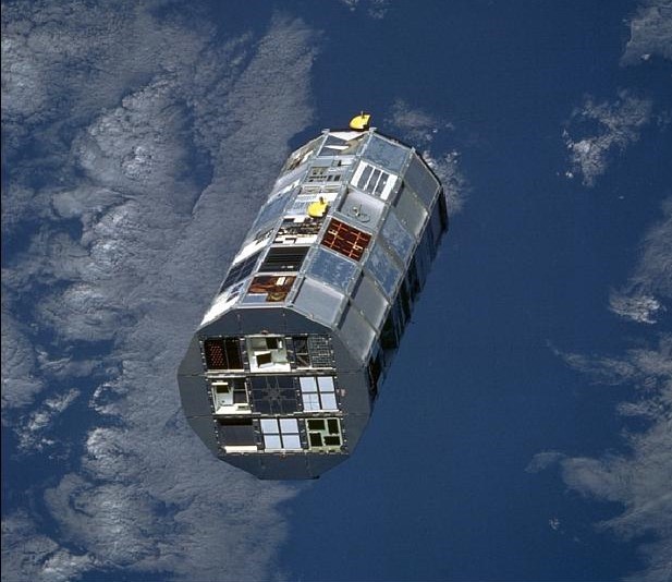 A large roughly cylindrical satellite against the blue background of the Earth